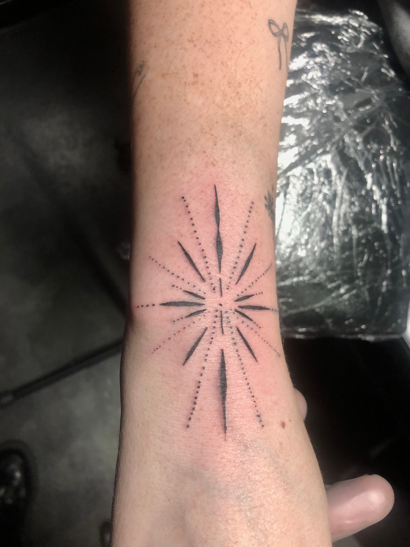 Hand-poke starburst forearm tattoo by Rondon Neto